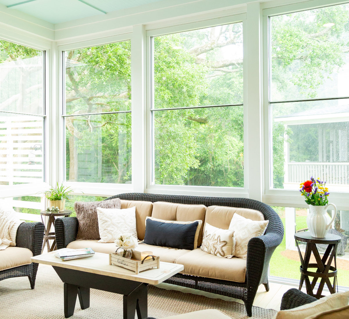 Interior image of a glass sunroom with a white couch and decor